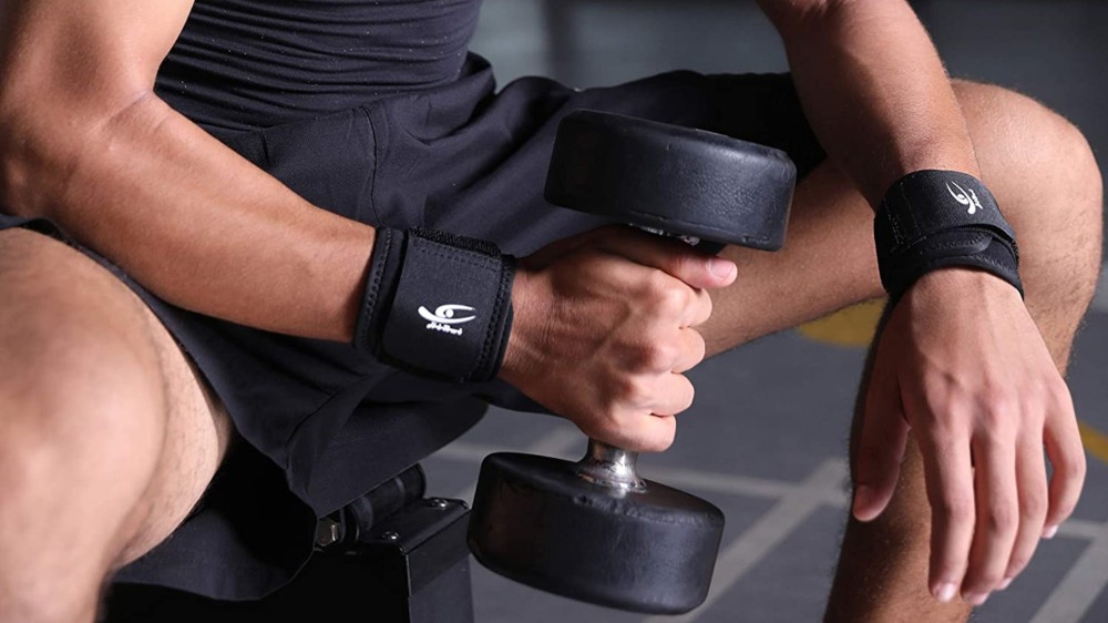 A man wearing two black wrist braces while lifting a dumbell.