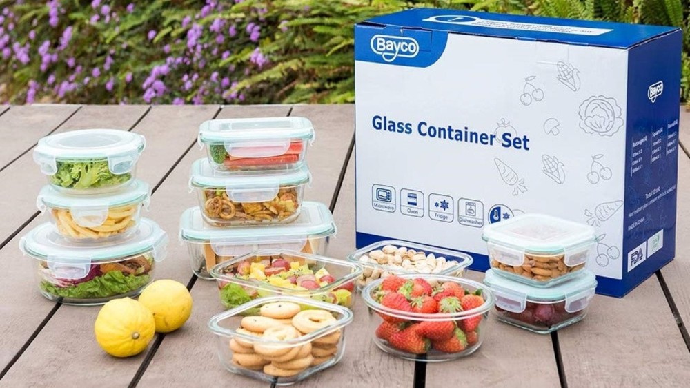 Twelve glass containers with fruits, vegetables, salads, and cookies inside.