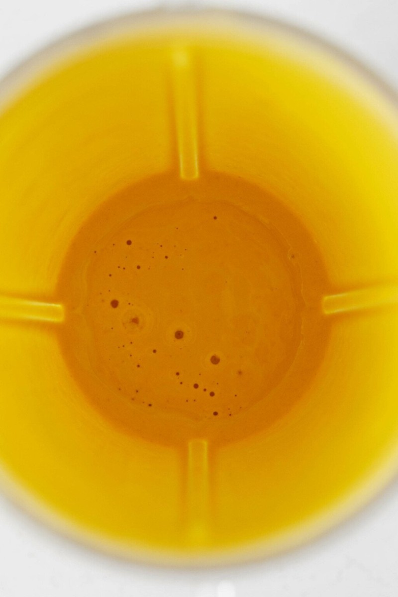 An overhead image of a creamy yellow sauce inside a small, personal sized blender.